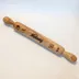 Wood rolling pin with dramatic natural grain, engraved name "Melany" centered on the barrel with flower motifs on either side