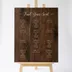 Personalized wedding seating chart sign in walnut-stained birch, guest names arranged in tidy columns.