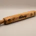 Angled studio view of the wood rolling pin showing the turned handle knobs and grain running the length of the barrel