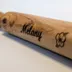 Close-up of the laser-engraved script name and flower detail on the wood barrel, showing the depth of the burn line against the grain
