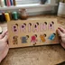 Two hands holding the wood name puzzle spelling Briana to show its actual size, on a wooden table with sewing spools in the background