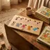 Wood name puzzle spelling Briana styled on a rustic wooden trunk with a coffee mug, stacked vintage children's books, and wooden blocks on a woven rug