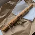 Rolling pin tied with twine and a small dried-flower sprig, resting on kraft paper and tissue paper as a gift presentation