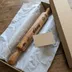 Rolling pin packed in tissue paper inside an open kraft gift box with a blank kraft note card