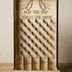 Baltic birch prize drop board standing upright on its slotted base against a warm neutral backdrop, every peg casting its own small shadow