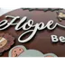 Angled side view of the sign showing the raised, layered depth of the letters and animal figures